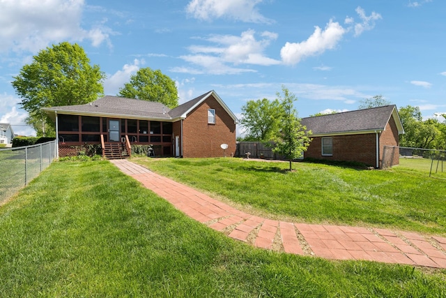back of property with a lawn, brick siding, a fenced backyard, and a sunroom