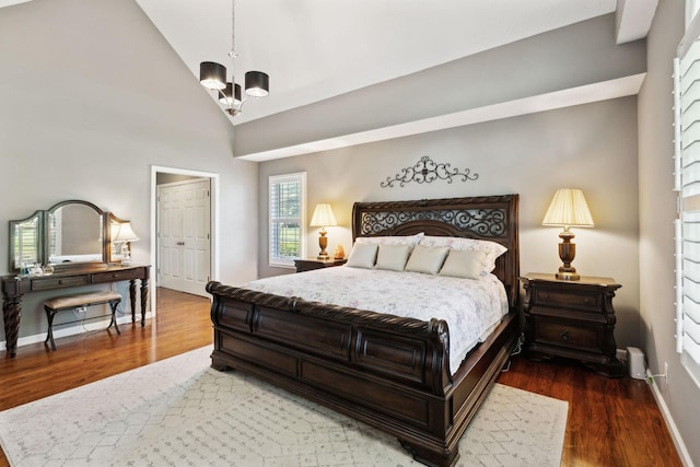 bedroom with an inviting chandelier, baseboards, high vaulted ceiling, and wood finished floors