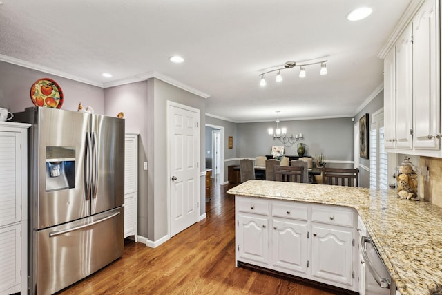 kitchen featuring an inviting chandelier, crown molding, a peninsula, white cabinets, and stainless steel appliances