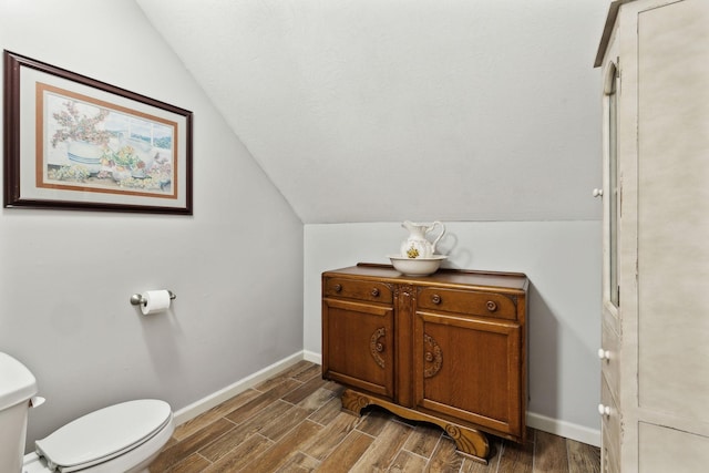bathroom with toilet, baseboards, wood finished floors, and lofted ceiling