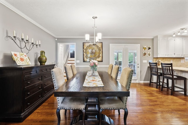 dining room with wood finished floors, stairway, baseboards, a notable chandelier, and ornamental molding