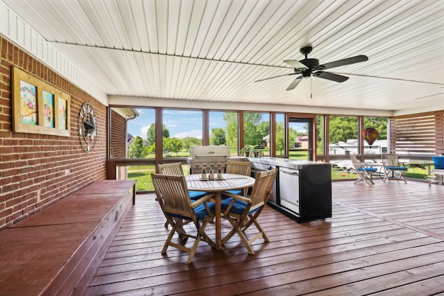 sunroom featuring brick wall, a wooden deck, hardwood / wood-style flooring, and outdoor dining space