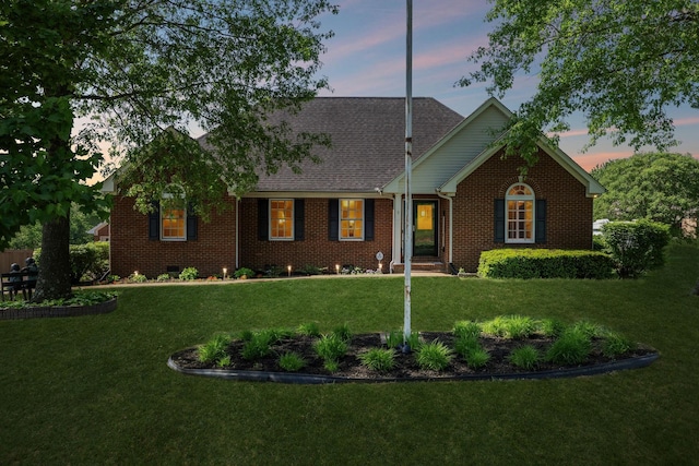 ranch-style house featuring brick siding, a shingled roof, and a front lawn