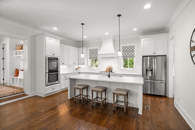kitchen with custom exhaust hood, a kitchen breakfast bar, white cabinetry, tasteful backsplash, and appliances with stainless steel finishes