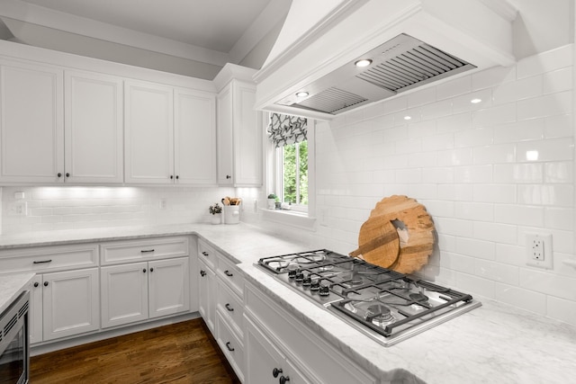 kitchen featuring premium range hood, white cabinets, light stone counters, appliances with stainless steel finishes, and backsplash