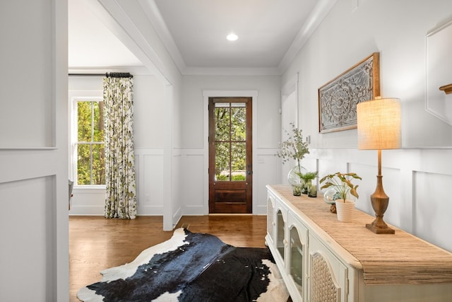 entryway featuring a decorative wall, wainscoting, wood finished floors, and plenty of natural light