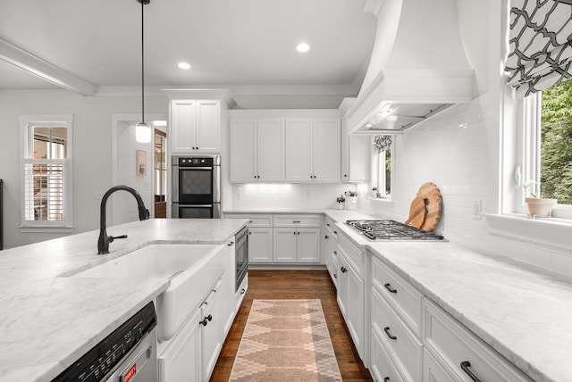 kitchen with white cabinetry, appliances with stainless steel finishes, a sink, and premium range hood