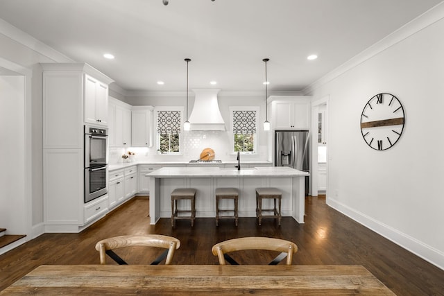 kitchen with a sink, a kitchen island with sink, dark wood finished floors, stainless steel appliances, and custom exhaust hood
