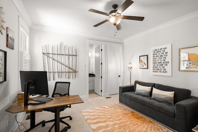 office space with baseboards, a ceiling fan, crown molding, and light carpet