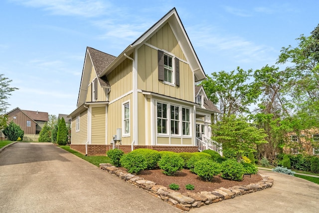 view of home's exterior featuring a shingled roof, board and batten siding, and driveway