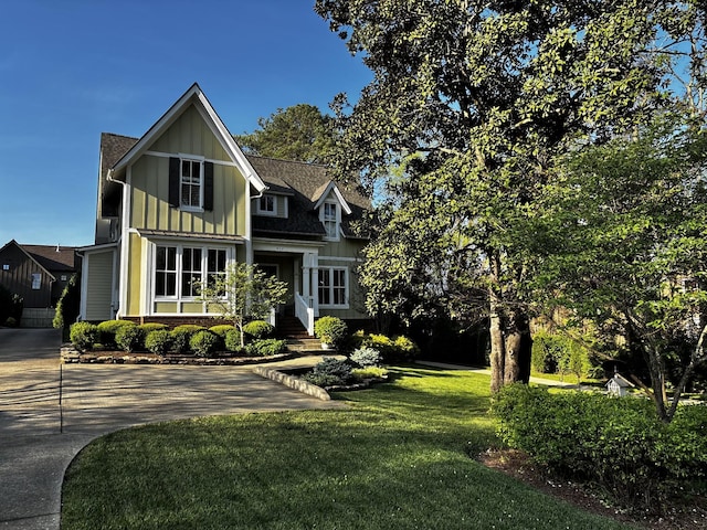 view of front facade with a front lawn, board and batten siding, and driveway