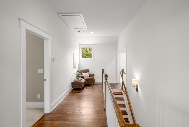 hallway featuring baseboards, attic access, wood finished floors, and an upstairs landing