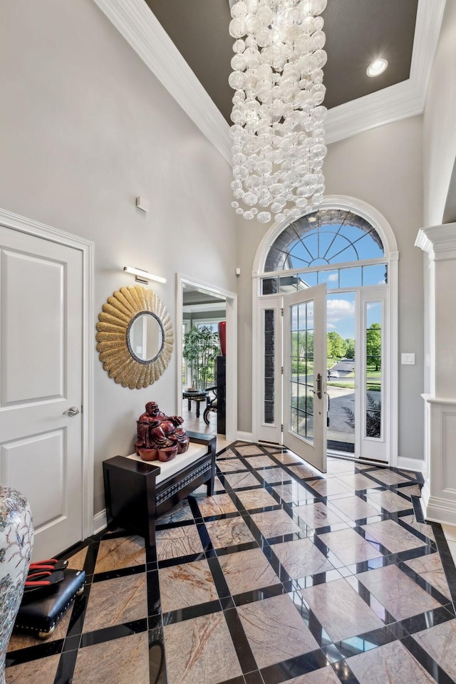 foyer entrance featuring crown molding, baseboards, french doors, and a towering ceiling