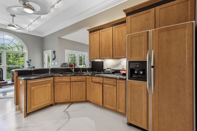 kitchen featuring a peninsula, dark countertops, paneled refrigerator, and brown cabinets