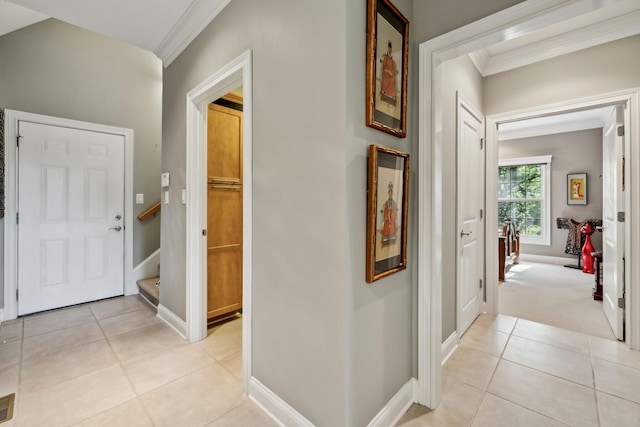 hall featuring baseboards, ornamental molding, light tile patterned floors, and stairway