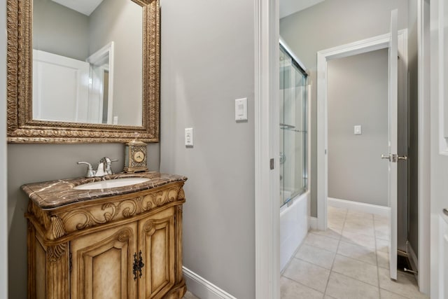 bathroom featuring vanity, baseboards, tile patterned floors, and shower / bath combination with glass door