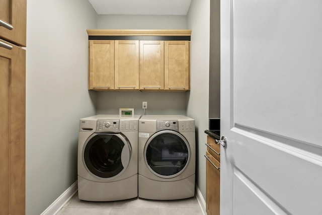 washroom with light tile patterned floors, baseboards, cabinet space, and washing machine and clothes dryer