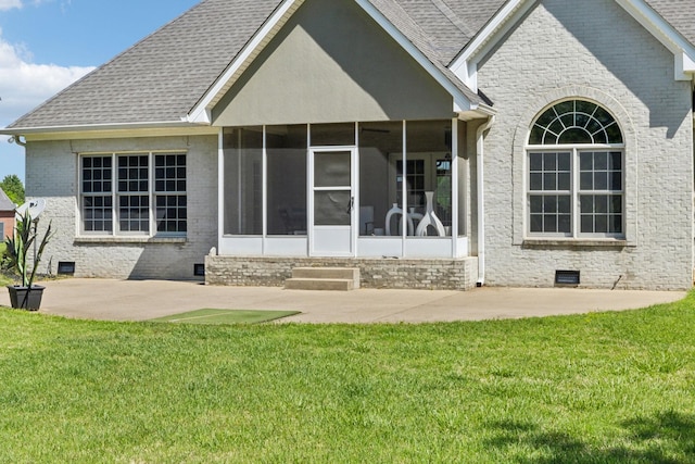 rear view of house with brick siding, a sunroom, crawl space, a patio, and a yard