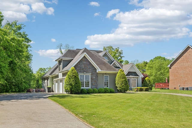 craftsman-style home featuring stone siding, a garage, stucco siding, a front yard, and concrete driveway