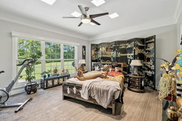 carpeted bedroom with a ceiling fan, a skylight, and ornamental molding