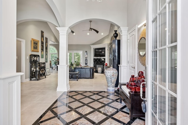 foyer featuring decorative columns, baseboards, high vaulted ceiling, arched walkways, and a ceiling fan