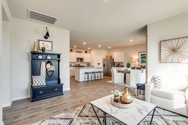 living area featuring visible vents, recessed lighting, light wood finished floors, and baseboards