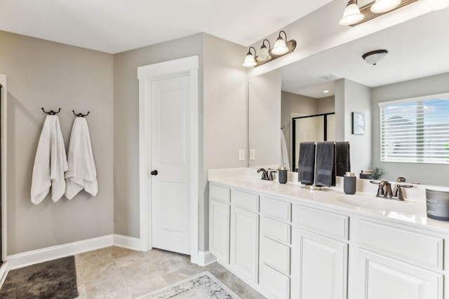 bathroom with double vanity, a sink, baseboards, and a stall shower
