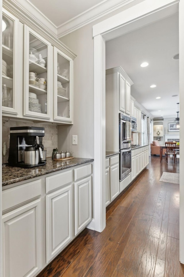 bar featuring crown molding, recessed lighting, dark wood-type flooring, and double oven