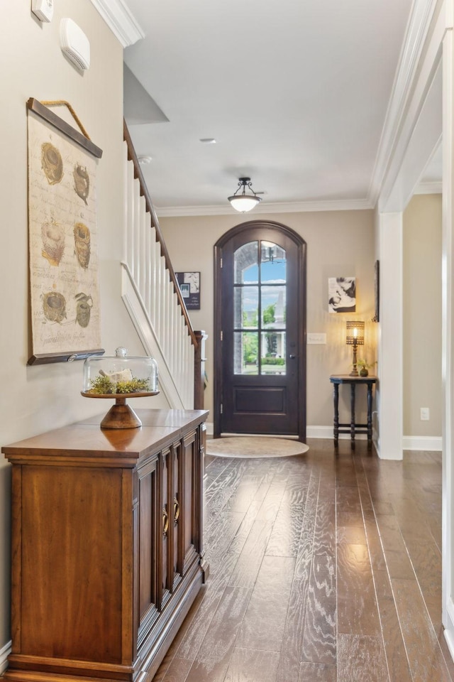 foyer entrance with arched walkways, ornamental molding, stairs, and dark wood-type flooring