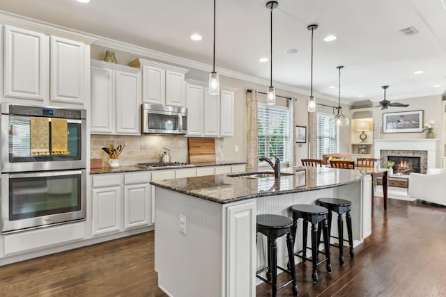 kitchen with ceiling fan, a breakfast bar, a sink, stainless steel appliances, and dark wood-style floors