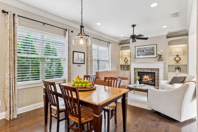 dining area featuring visible vents, ornamental molding, a fireplace, baseboards, and ceiling fan