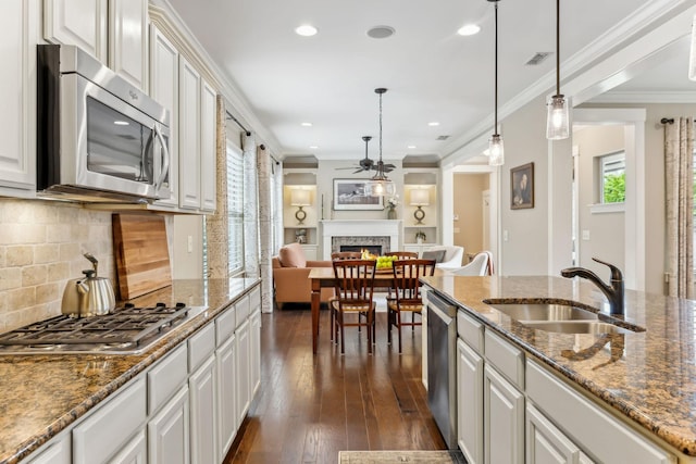 kitchen featuring a warm lit fireplace, ceiling fan, appliances with stainless steel finishes, a sink, and visible vents