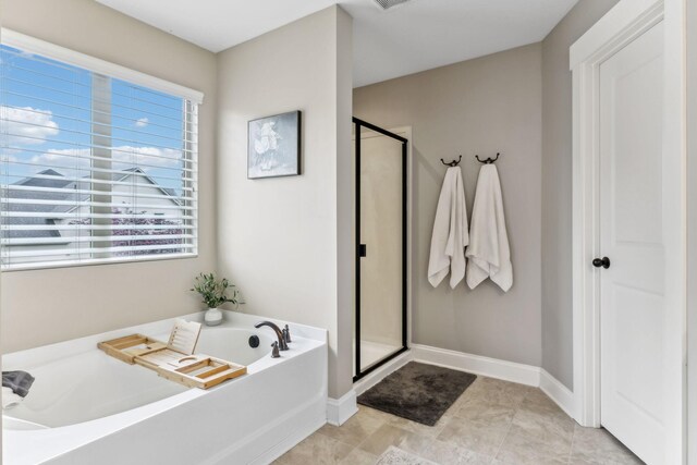 bathroom with baseboards, a stall shower, a bath, and visible vents
