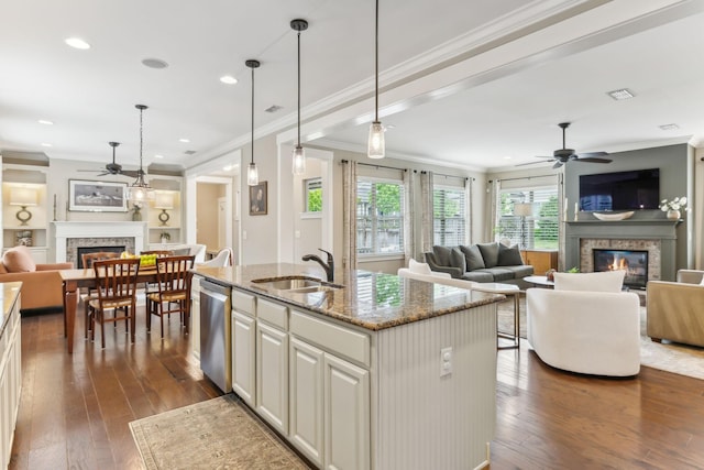 kitchen with stainless steel dishwasher, a ceiling fan, a glass covered fireplace, and open floor plan