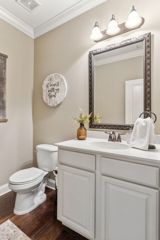 half bathroom featuring crown molding, toilet, visible vents, and wood finished floors