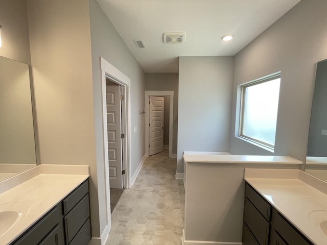 full bath with baseboards, two vanities, recessed lighting, and visible vents