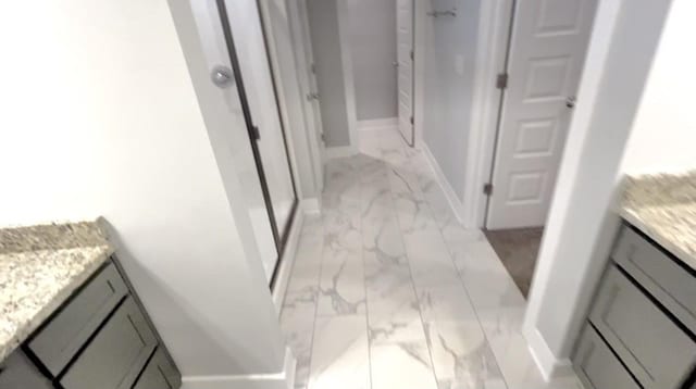 full bath with baseboards, a shower stall, marble finish floor, and vanity