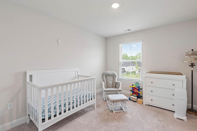 carpeted bedroom with visible vents, baseboards, and a crib