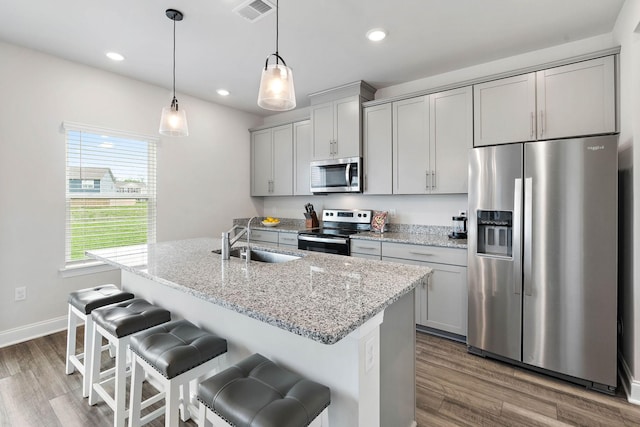kitchen featuring visible vents, dark wood-style flooring, gray cabinets, a sink, and stainless steel appliances