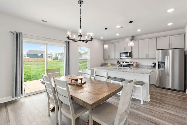dining space with visible vents, recessed lighting, light wood-type flooring, and an inviting chandelier