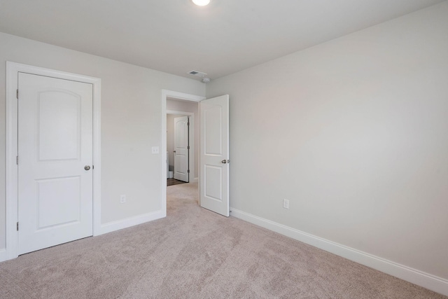 unfurnished bedroom featuring light colored carpet, baseboards, and visible vents