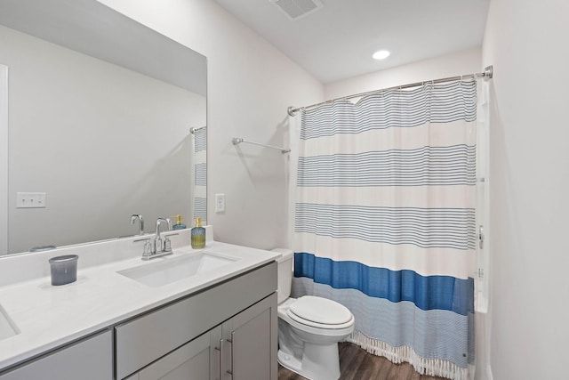bathroom with vanity, toilet, a shower with shower curtain, wood finished floors, and visible vents