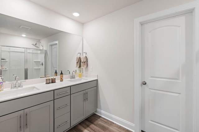 full bath featuring baseboards, a sink, wood finished floors, and a shower stall