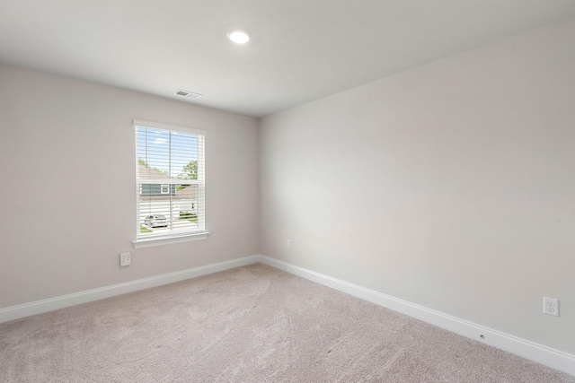 empty room featuring baseboards, light carpet, and visible vents