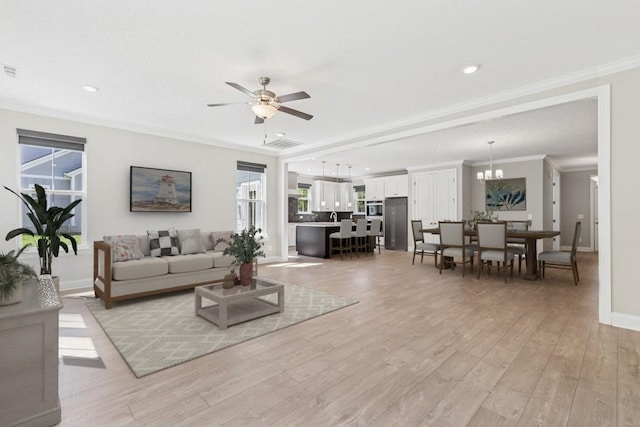 7205 Lake Rd, Fairview, TN 37062 - living room featuring ornamental molding, light wood finished floors, a ceiling fan, baseboards, and a chandelier