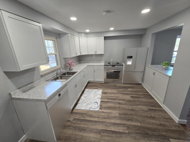 kitchen with a sink, stainless steel gas range oven, light countertops, dark wood finished floors, and white fridge with ice dispenser