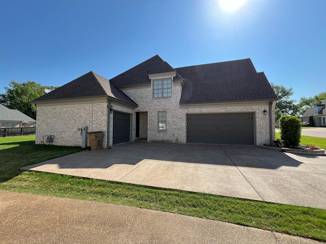 view of front of home with roof with shingles, an attached garage, a front lawn, brick siding, and concrete driveway
