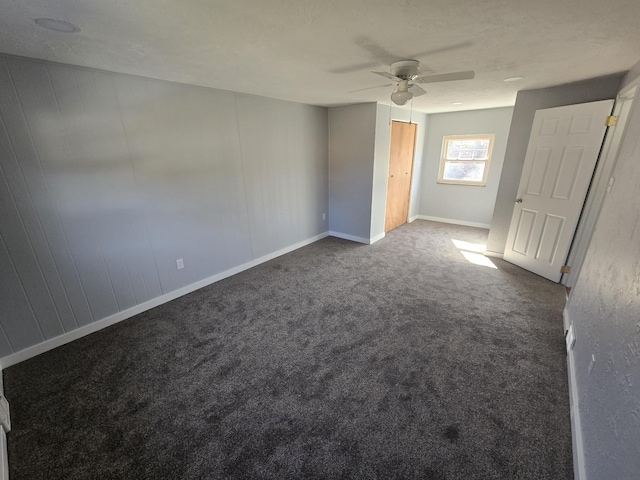 unfurnished bedroom with baseboards, ceiling fan, and dark carpet