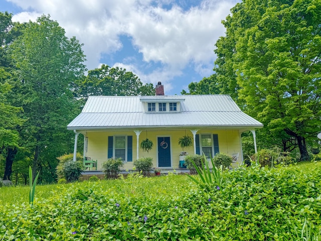 view of front facade featuring a porch, a chimney, and metal roof