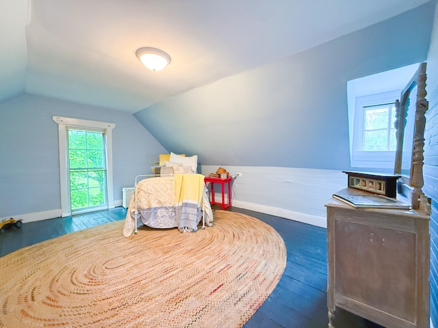bedroom featuring baseboards, wood finished floors, and vaulted ceiling